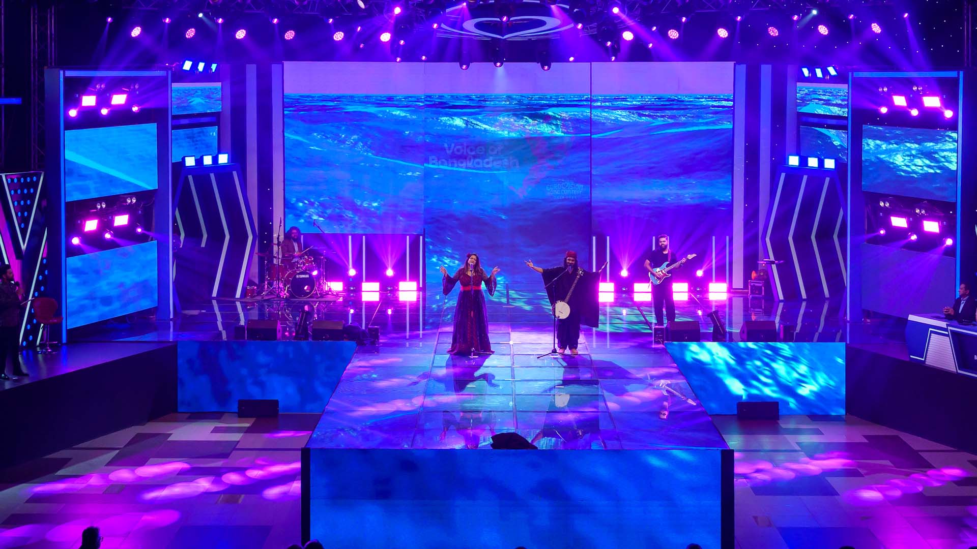 Singers and a musician on stage in front of an ocean-wave LED wall